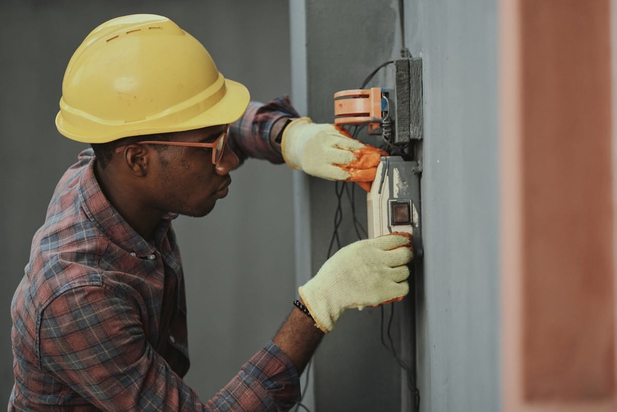 Technician working inside an open server chassis in a datacenter, installing or servicing hardware.