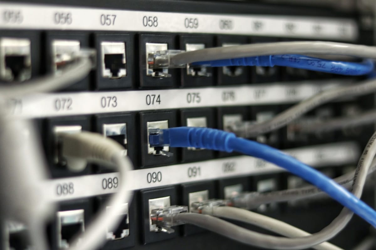 Network switch ports with many ethernet cables plugged in, green and orange link lights visible.