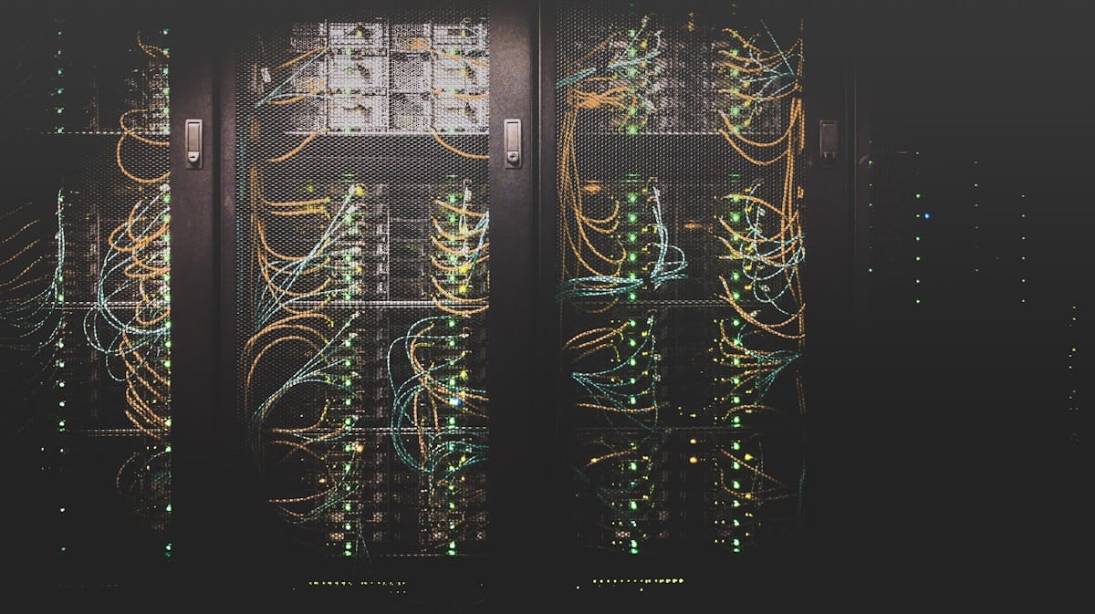 Rows of server racks in a datacenter aisle with perforated doors and cable management.